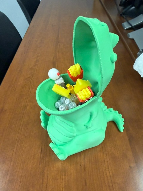 A green toy crocodile open to reveal various yellow, white, and purple items inside. On a wooden table.
