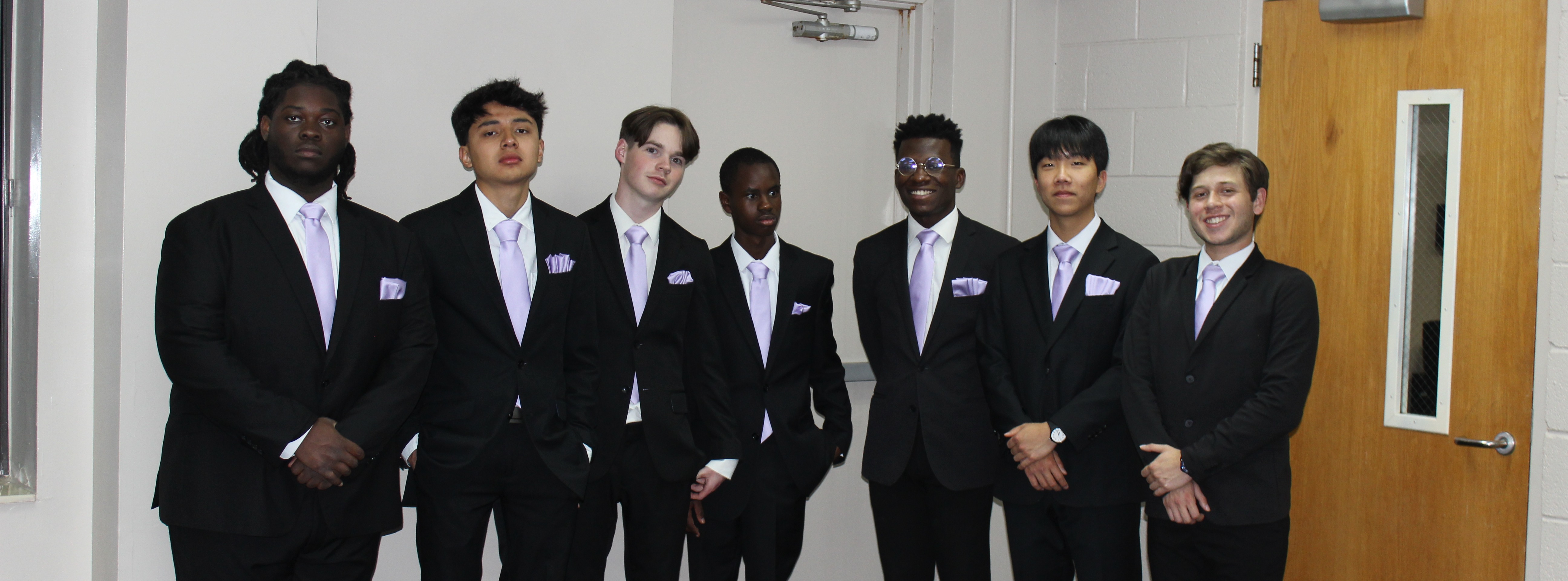 7 senior male students posing in tuxedos with lilac ties