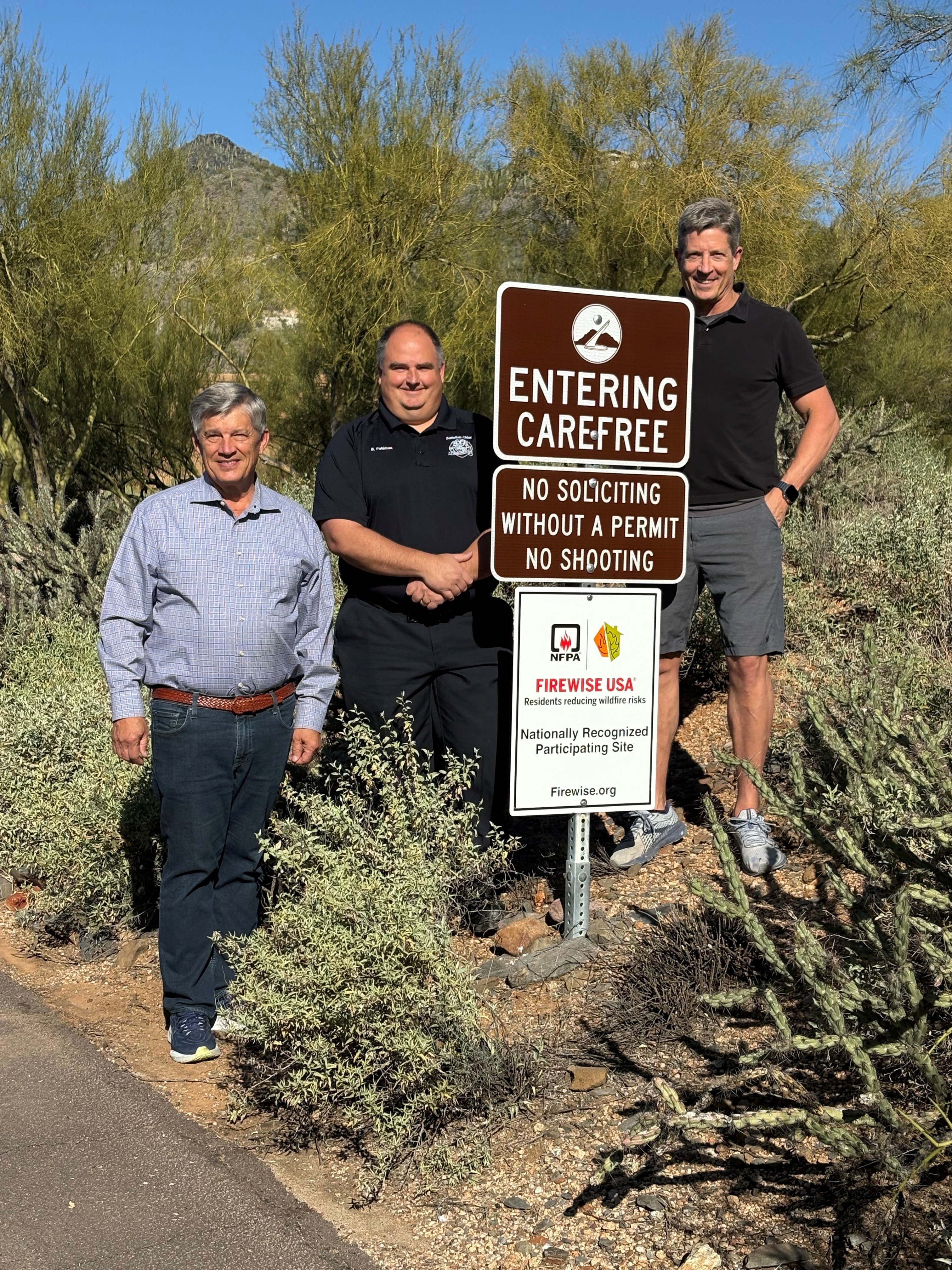 Community members and fire department member standing in front of Fireiwise Sign