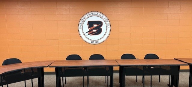 board table with Byron B behind it on an orange wall