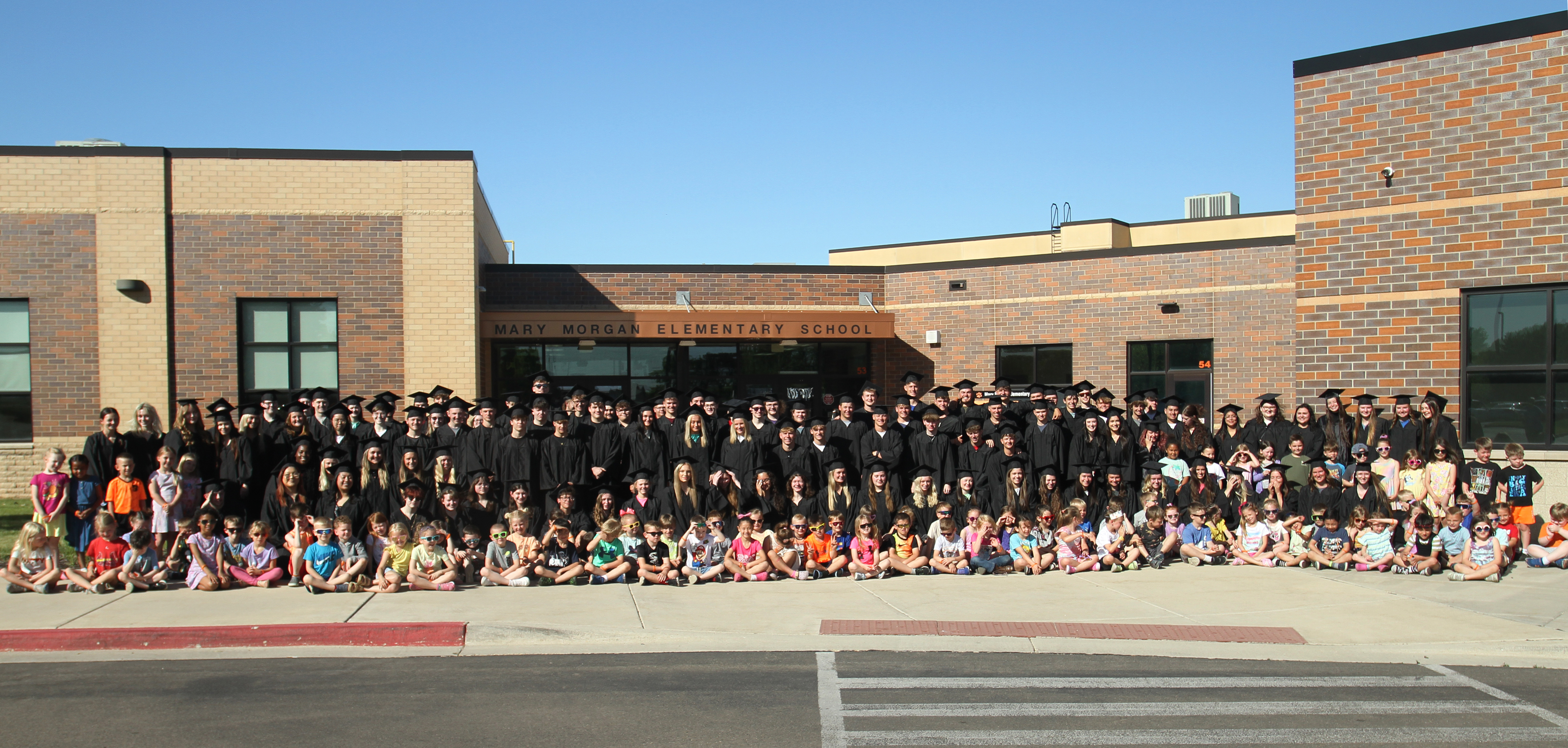seniors in grad gowns with kindergarten students