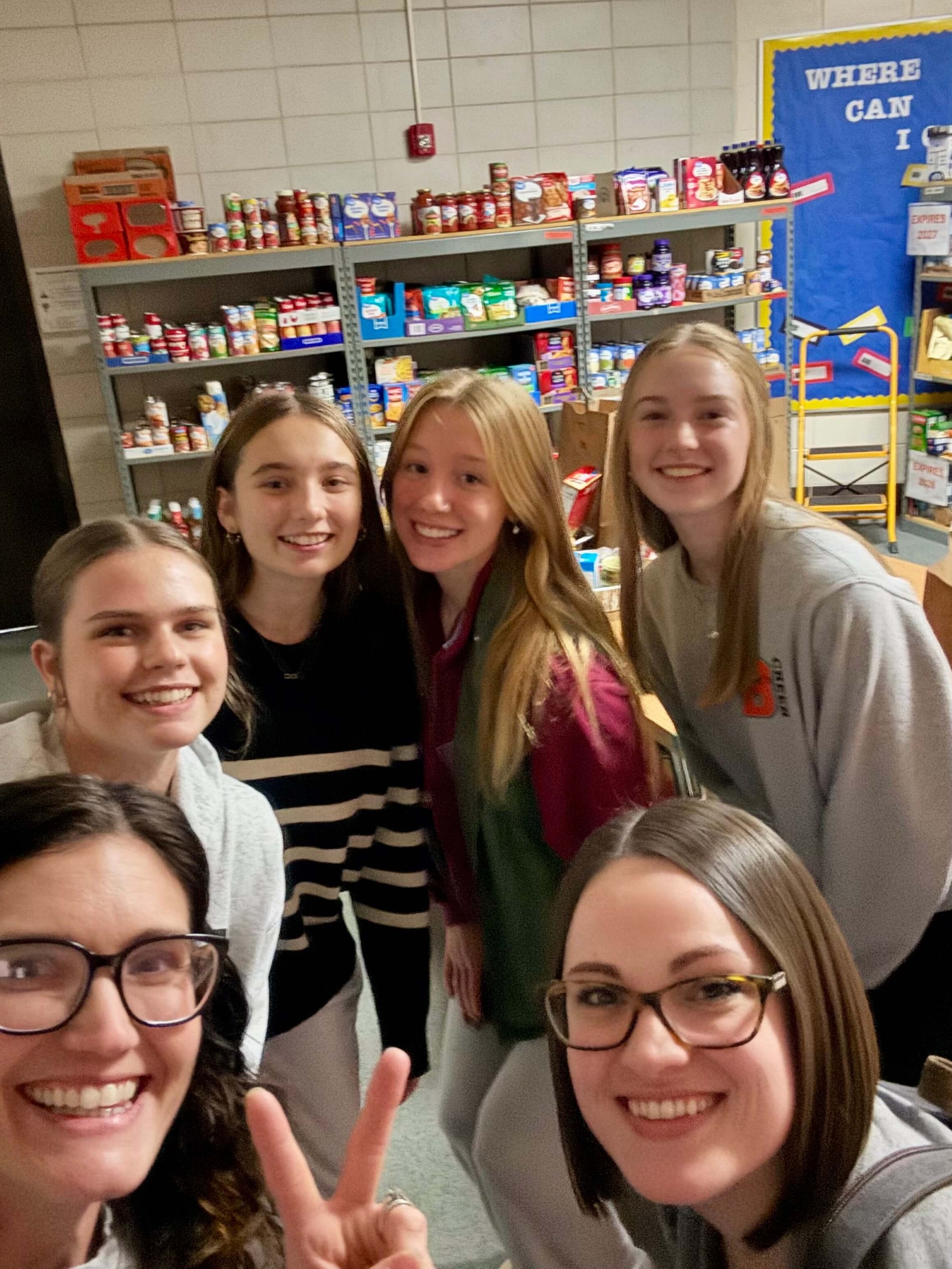 2 teachers and 5 students making thanksgiving donations to food pantry