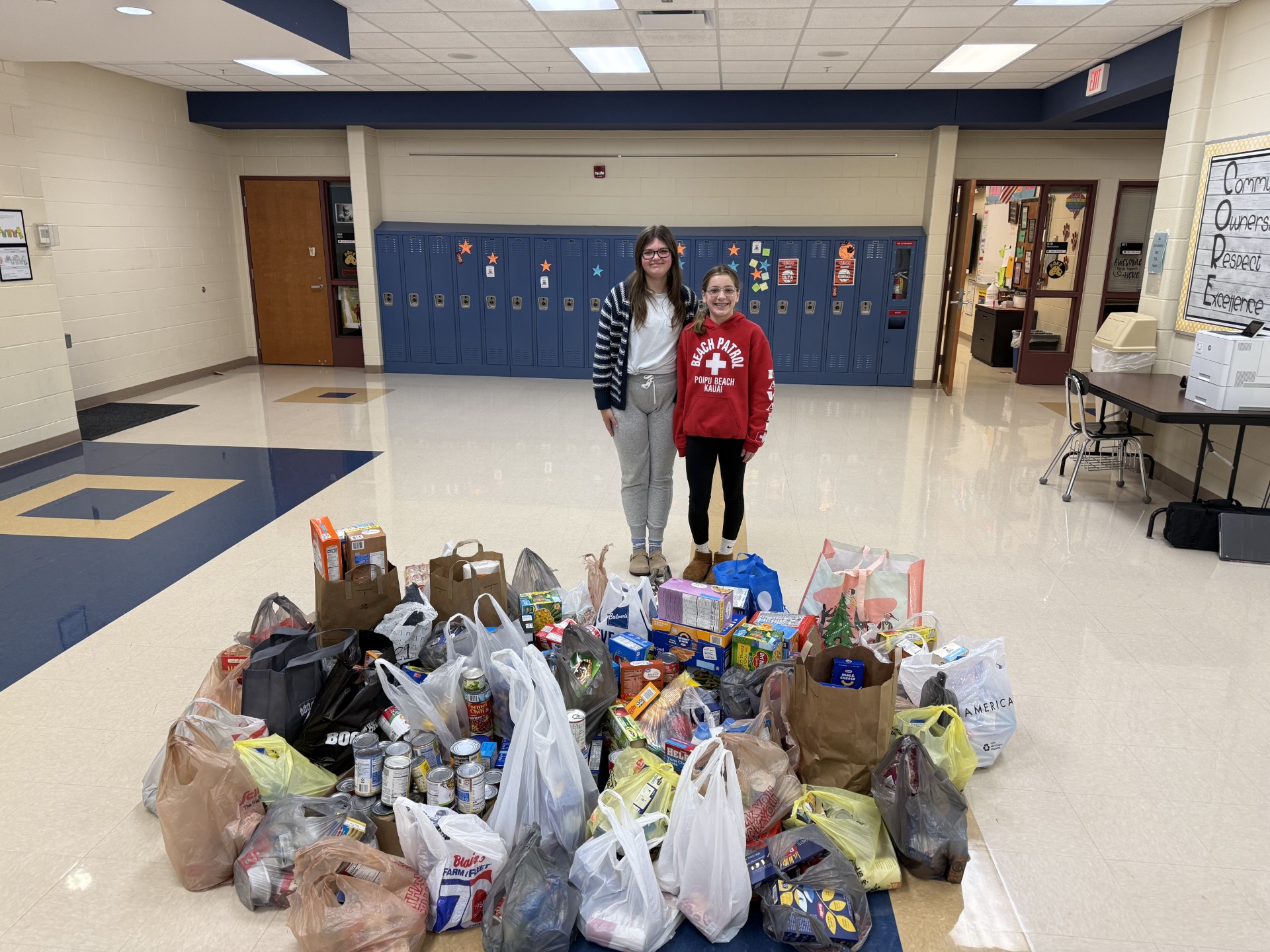 two students behind a pile of food donations