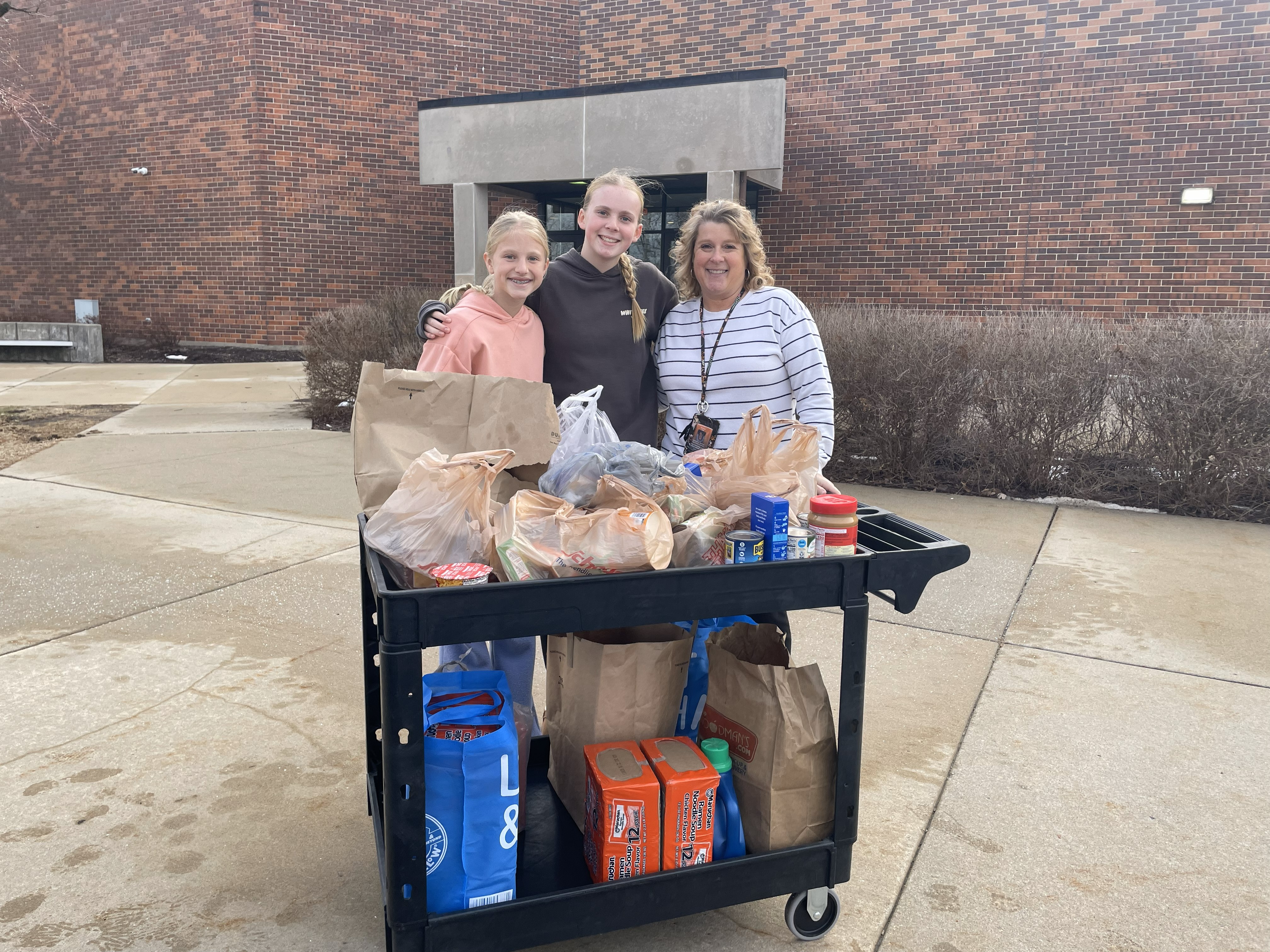 students with donation in front of cart