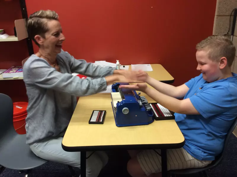 teacher of the visually impaired, teaching a student how to read braile code