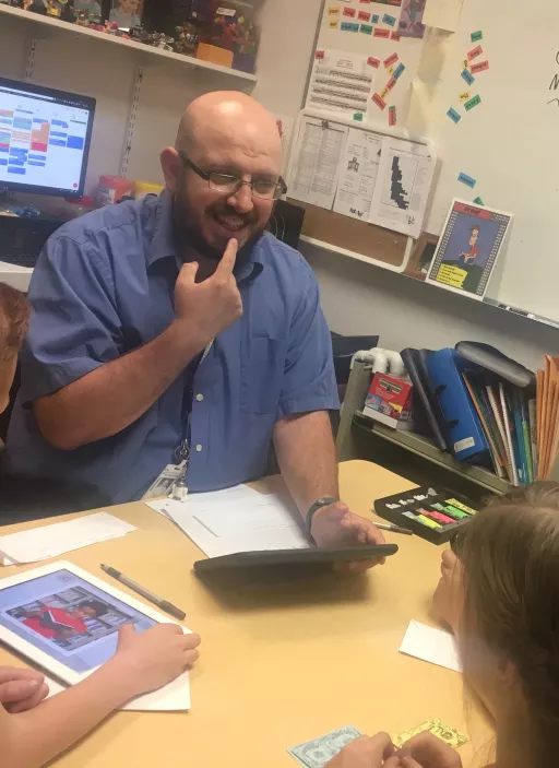 teacher talking with a little kid student, he is demonstrating how to spell something