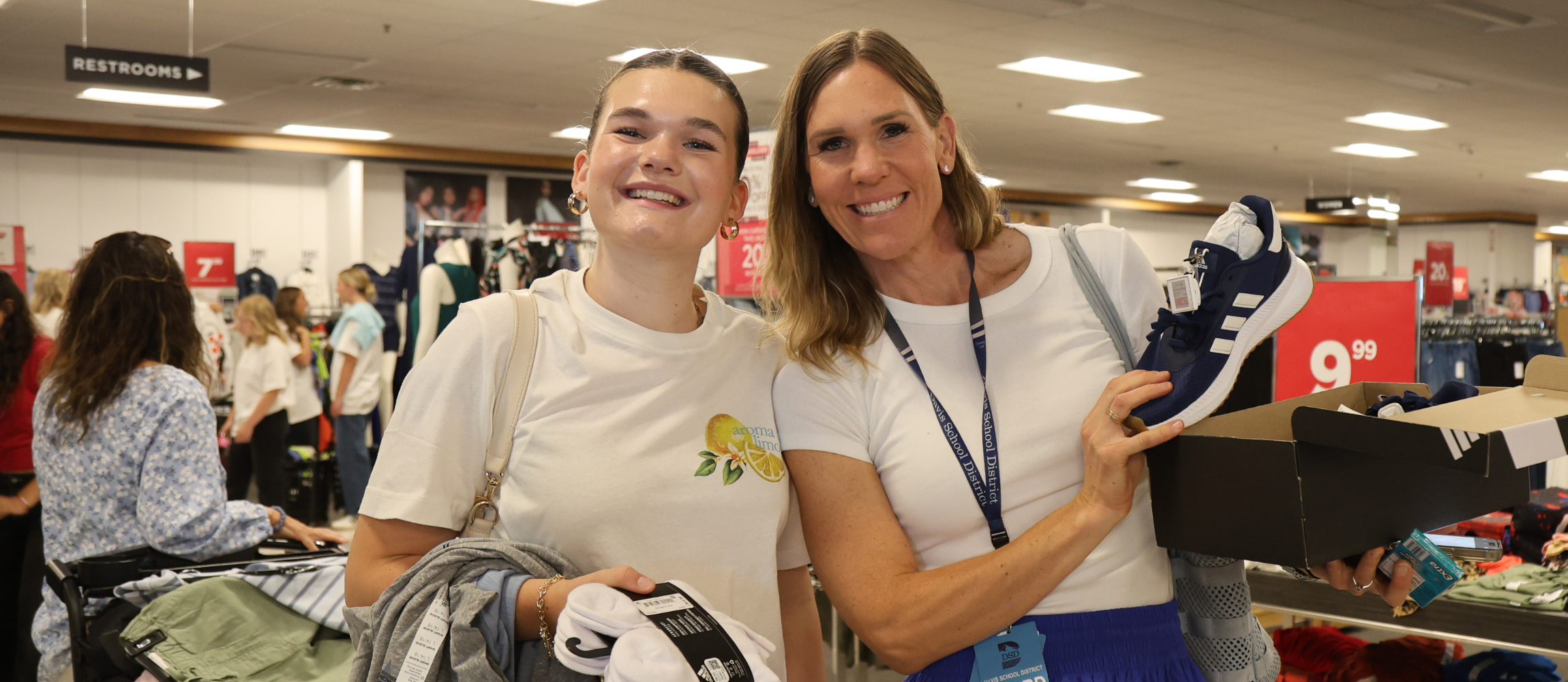 A photo of a student and a board member in Kohls holding up a box of shoes. 
