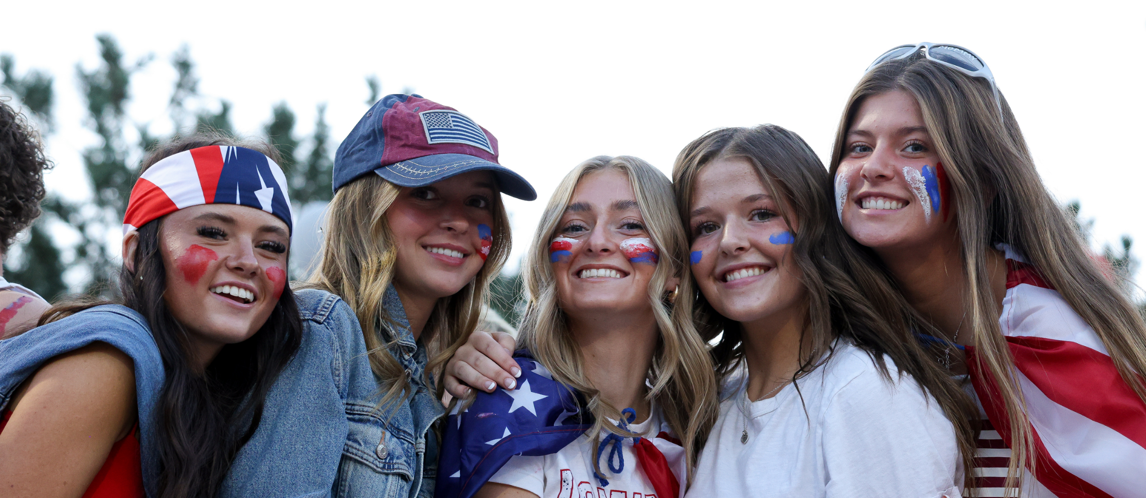 Five students decked out in red, white and blue smile at the camera.