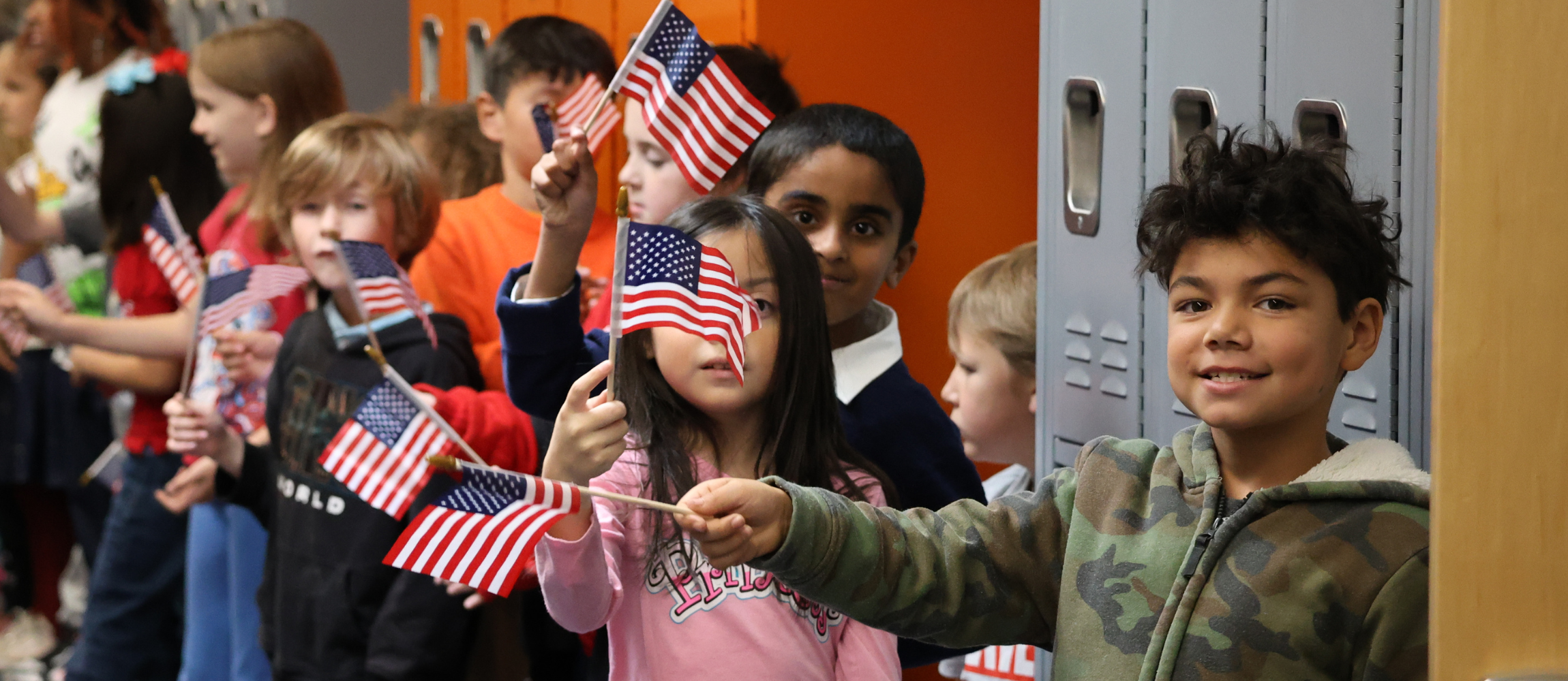 Students waving flags at Veterans Day parade. 