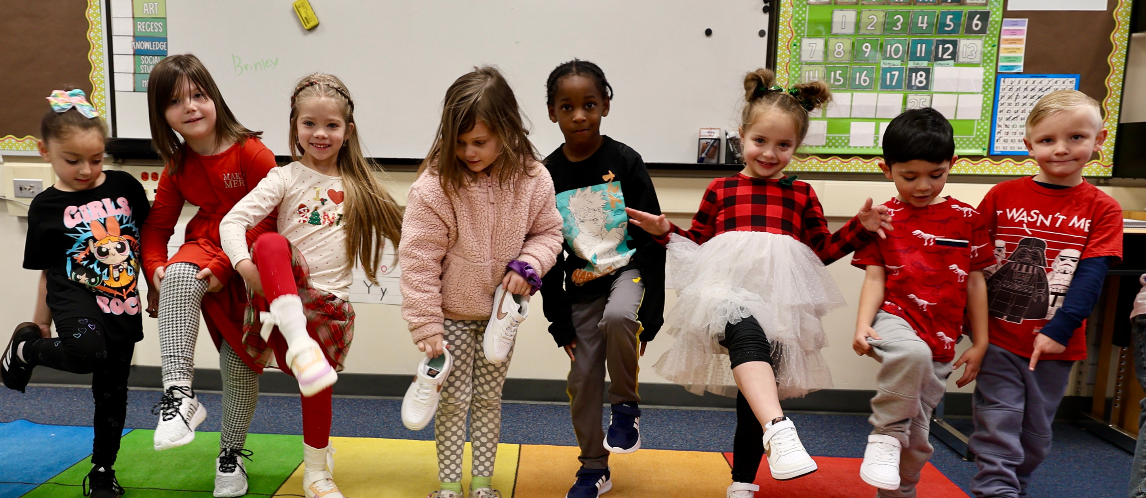 Kindergarten students in a line showing off their new shoes