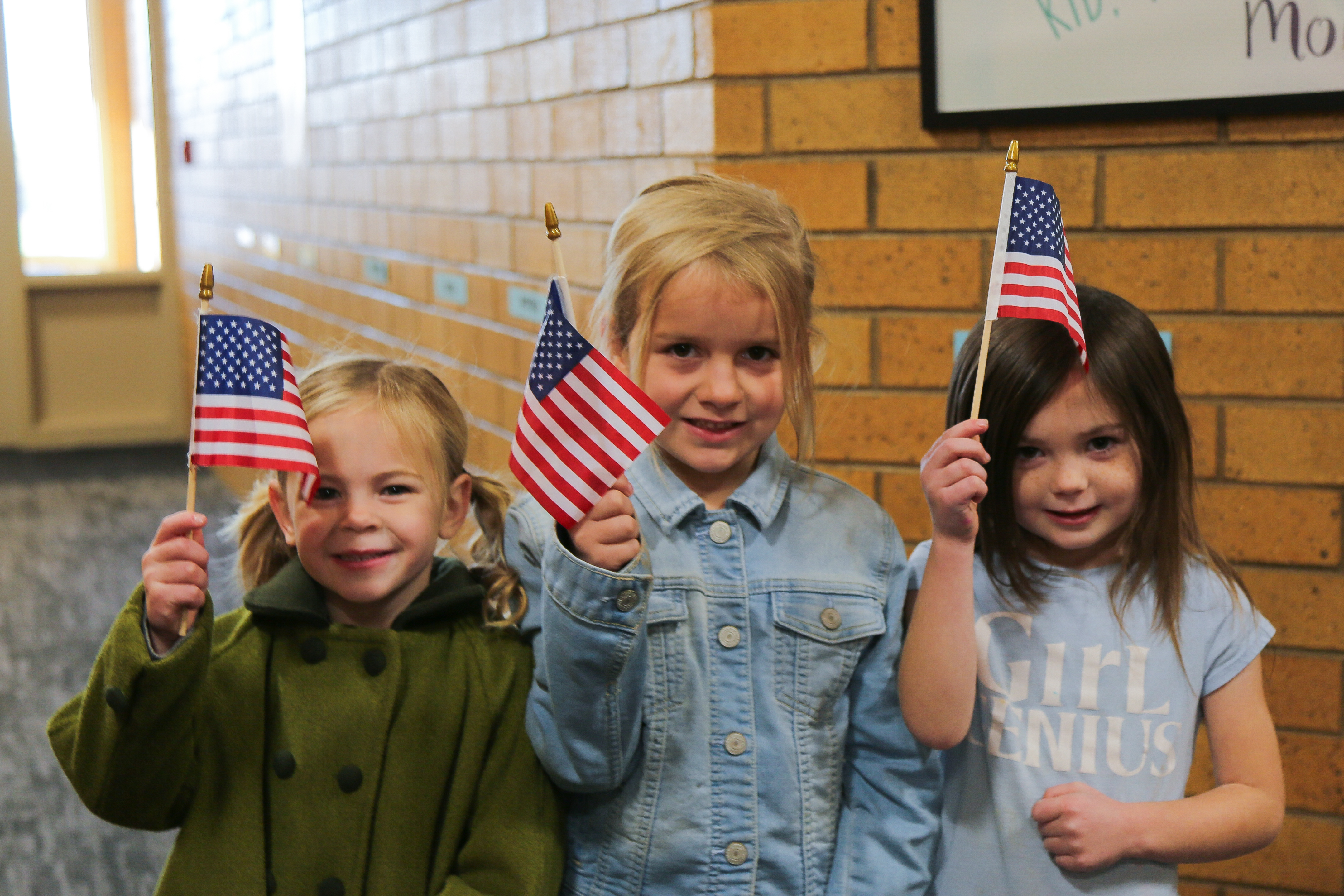 Three students holding up props while standing in front of a "Happy Constitution Day 2025" sign. 