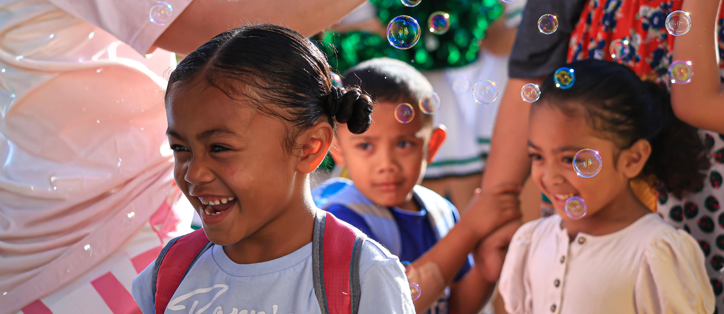 Student smiling as they walk through bubbles on the first day of school
