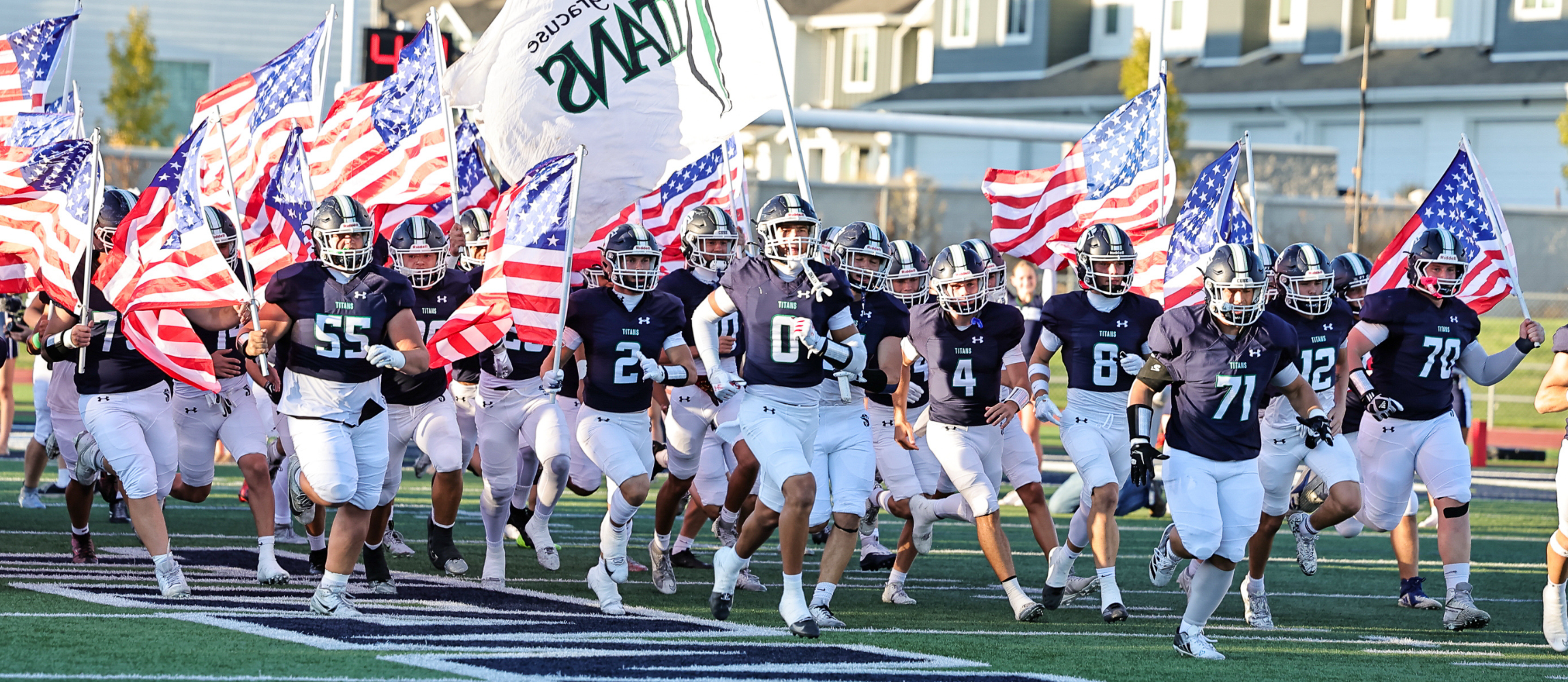 Syracuse High Football Team runs on the field with American Flags