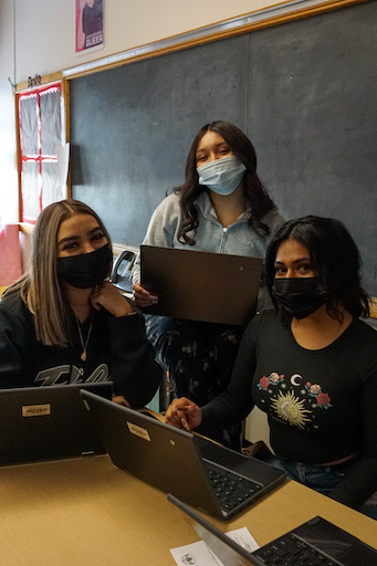 3 girls using their laptops and wearing masks 