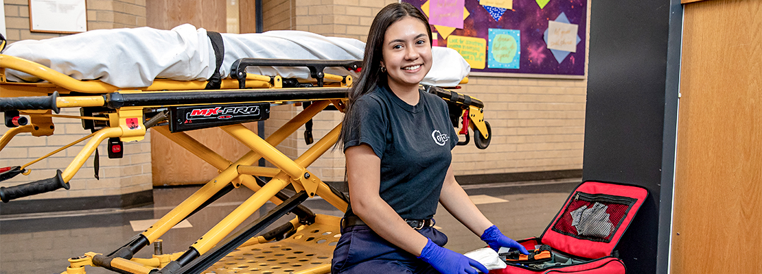 Emergency Medical Technician student next to a strecher