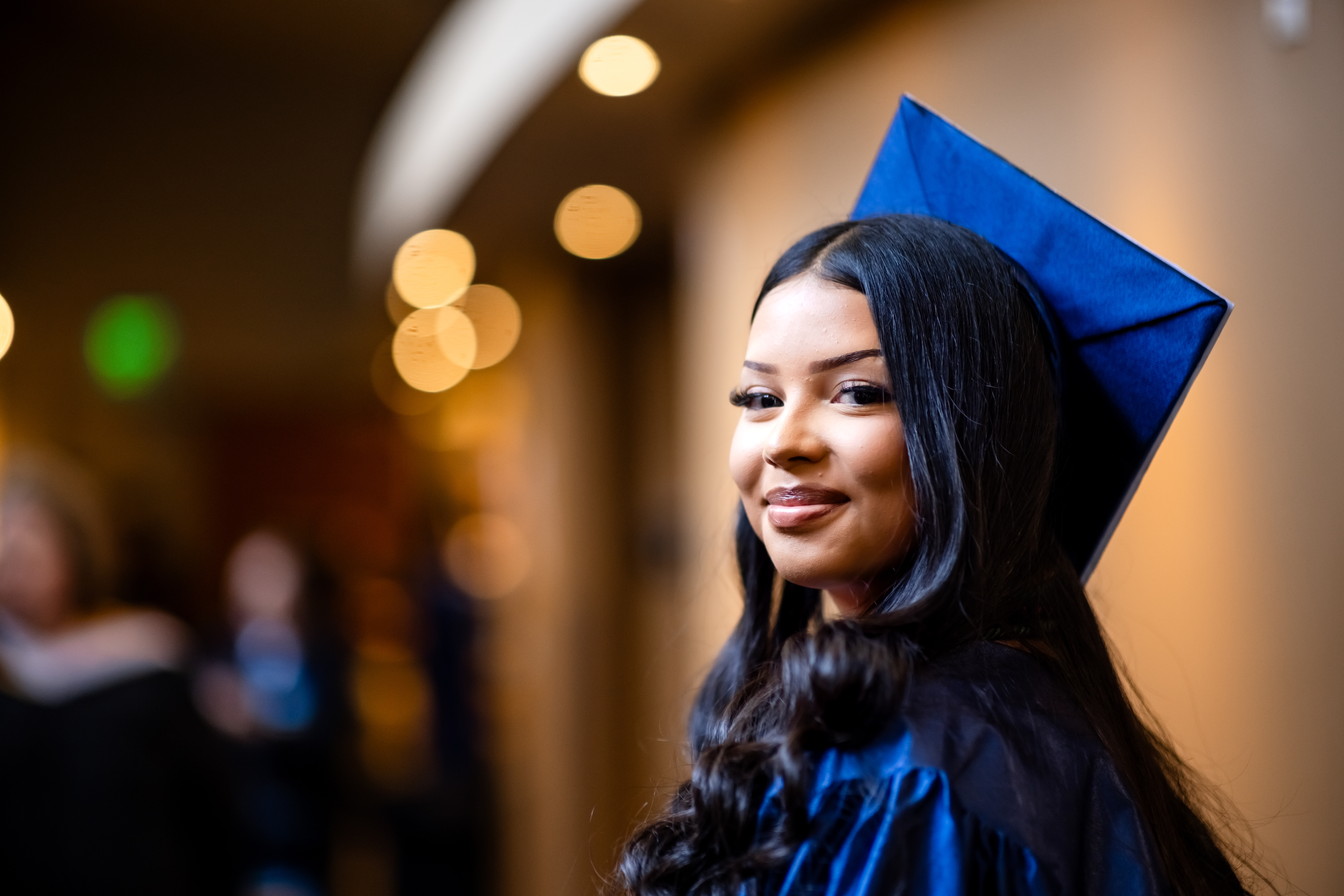 Photo of CEC Student looking back in their Graduation cap &amp; gown