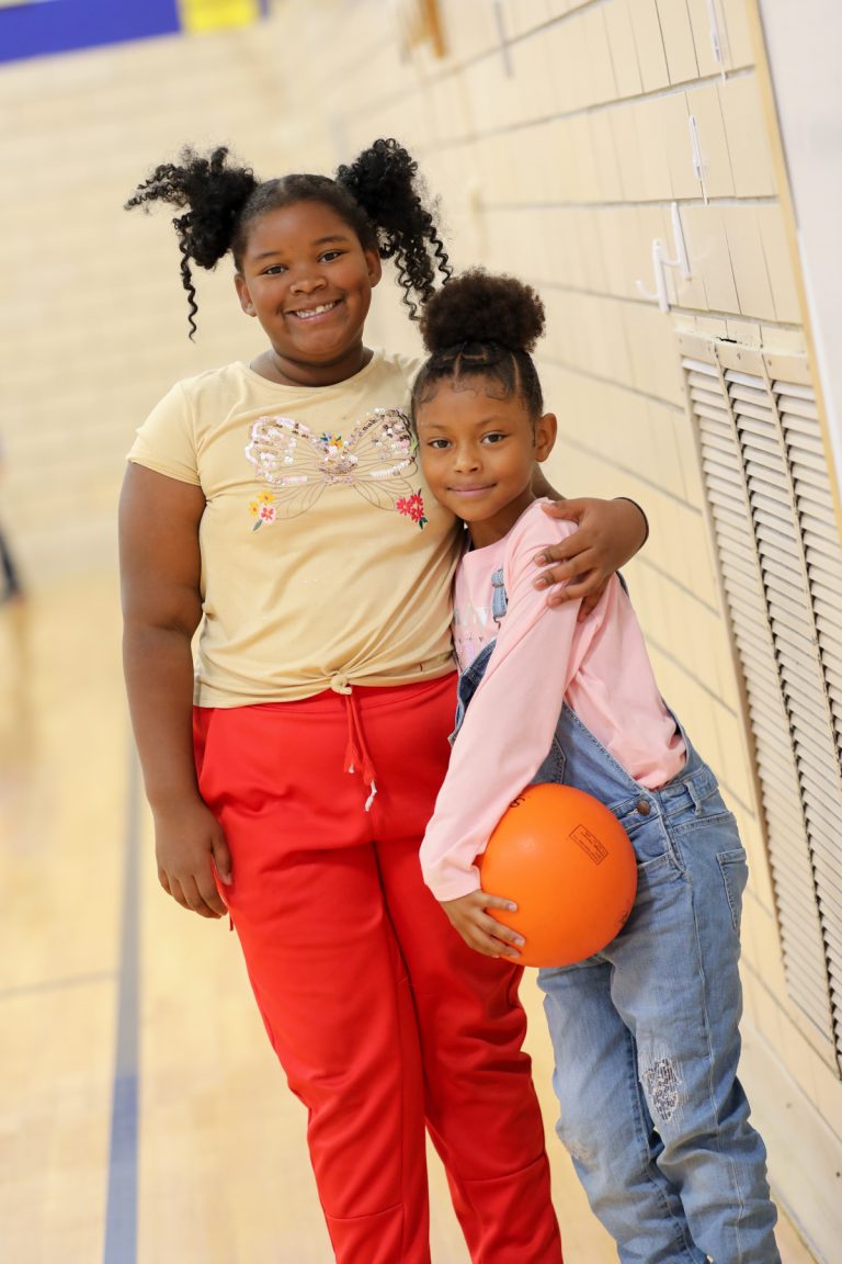 Students hugging and holding a basketball ball