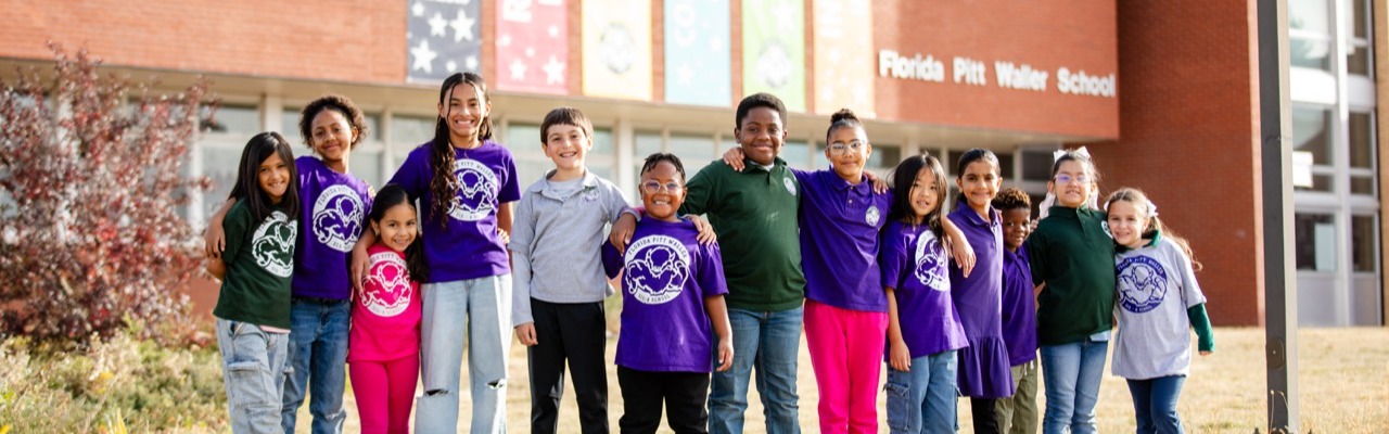 students posing for photo in front of school