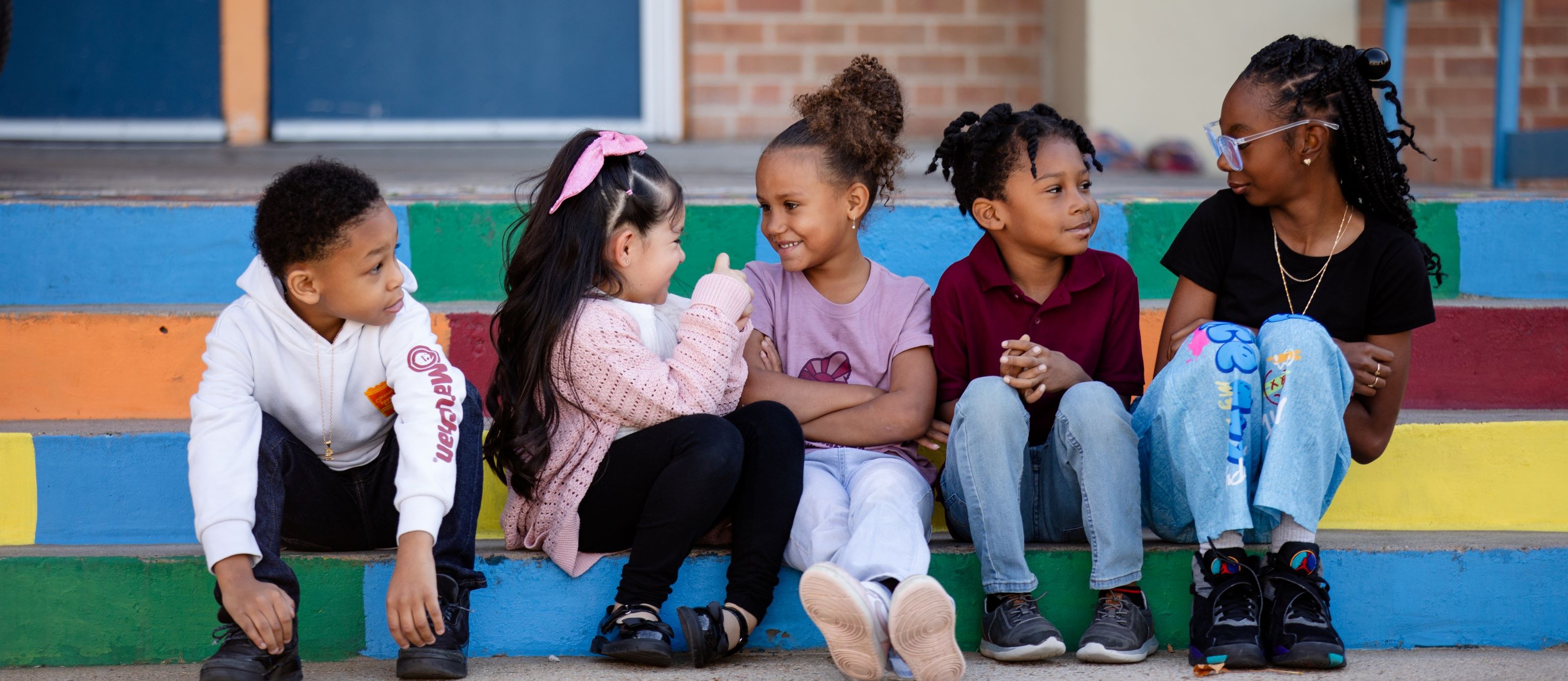 5 Hallett students sit on Hallett's steps smiling