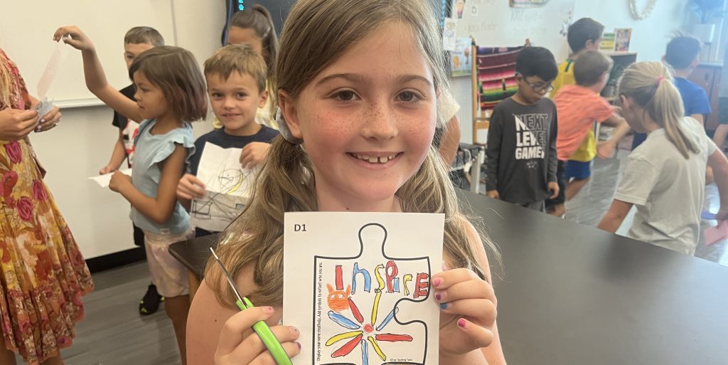 girl holding drawing in front of camera