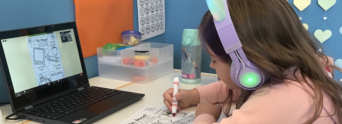 a girl with a laptop and coloring a paper