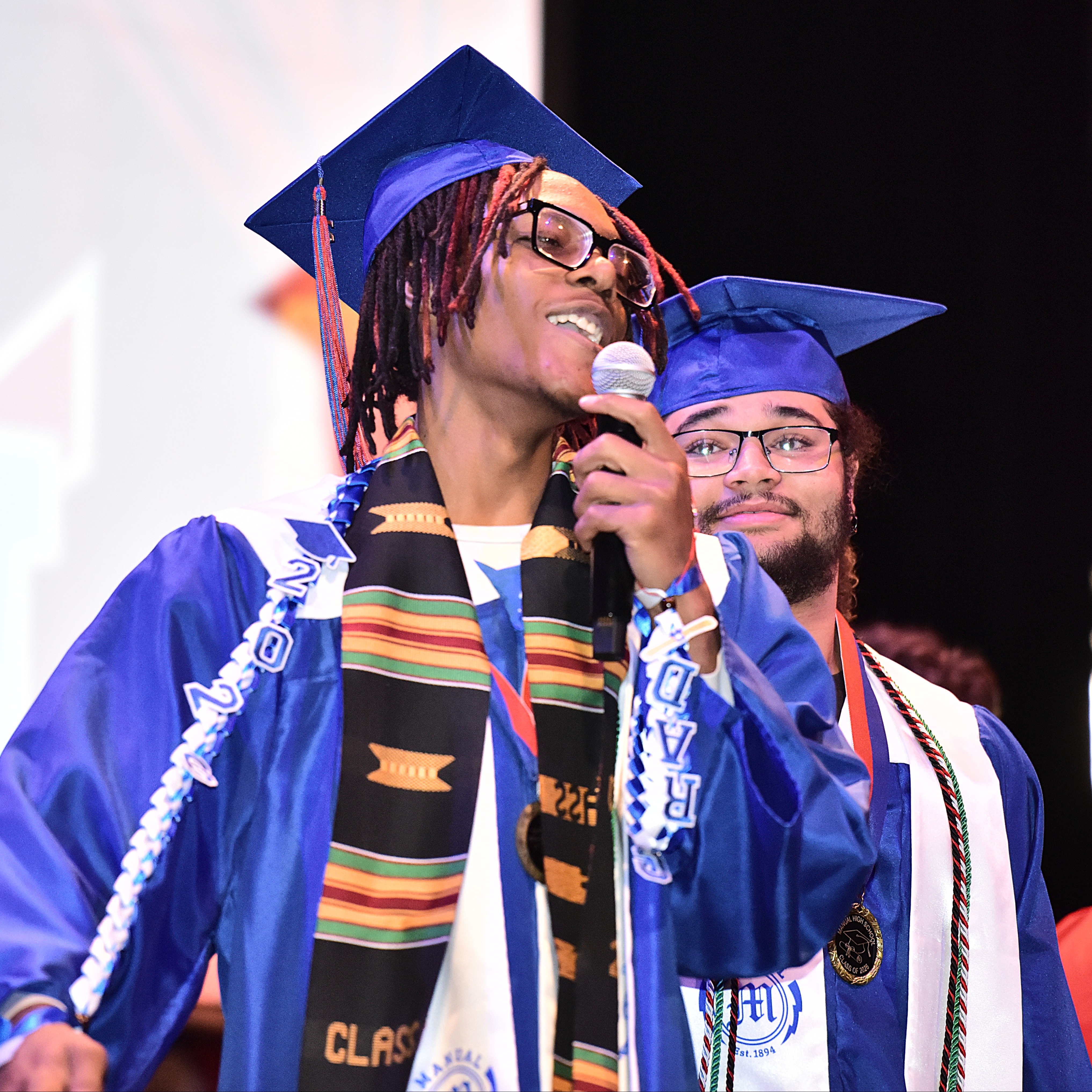 Manual student in grad cap speaks into the microphone