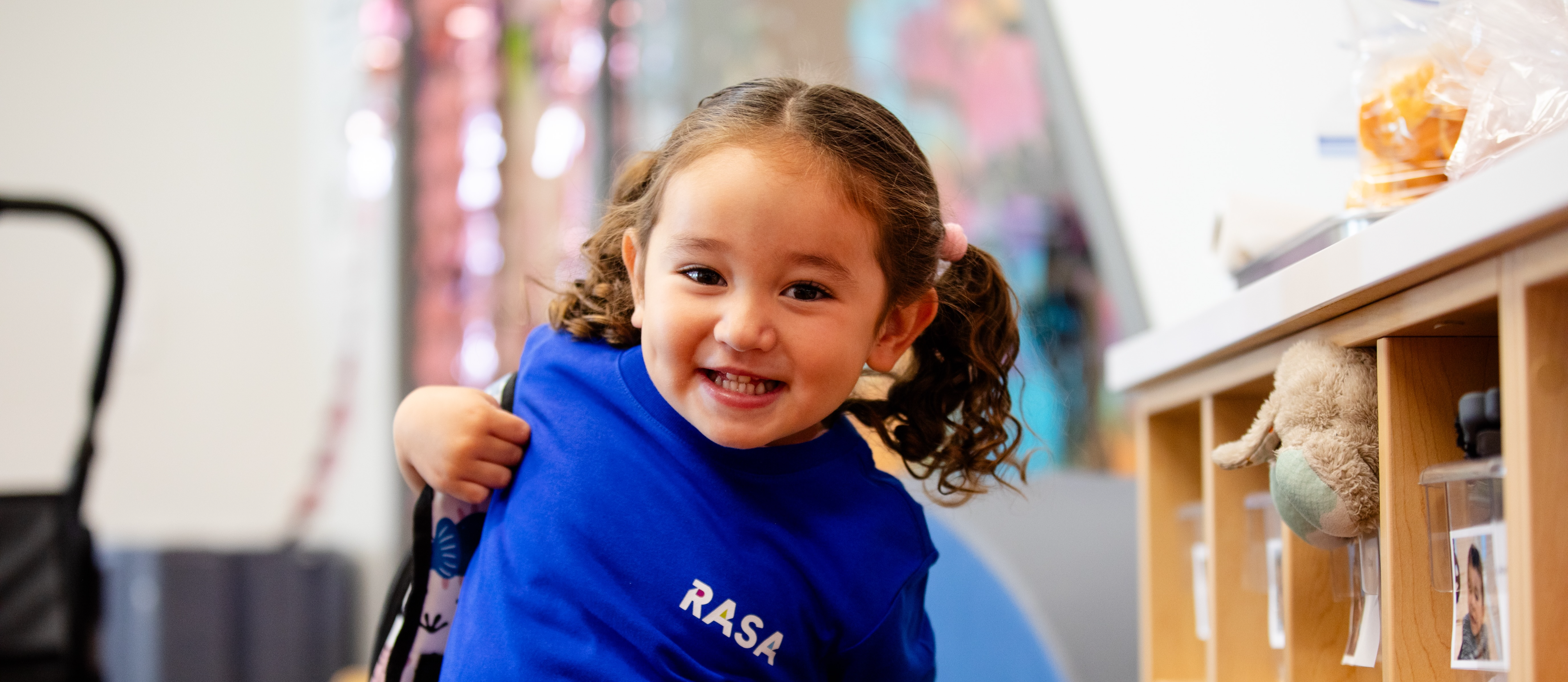 Student smiling and putting her backpack on with a blue shirt 