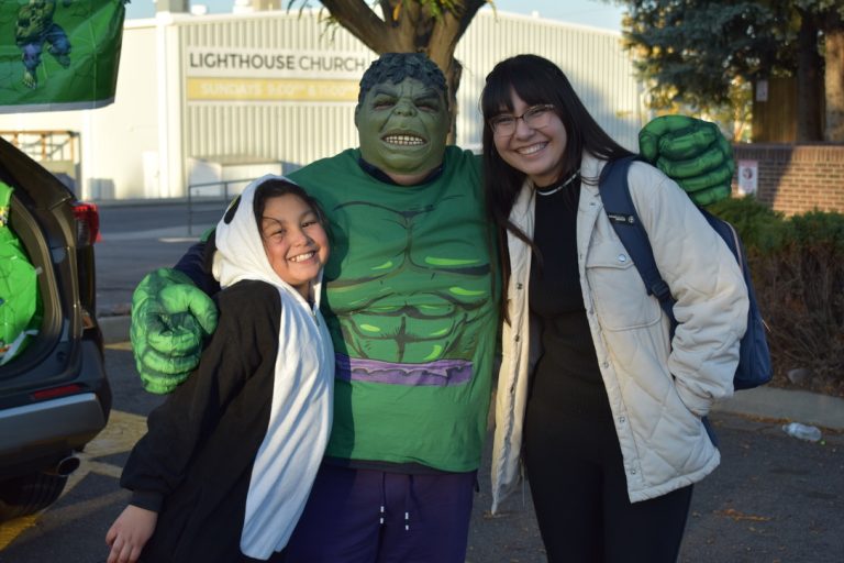 Two girls posing with a person dress up as Hulk
