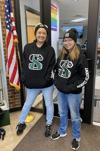 Two women smiling wearing matching Summit Academy sweatshirts