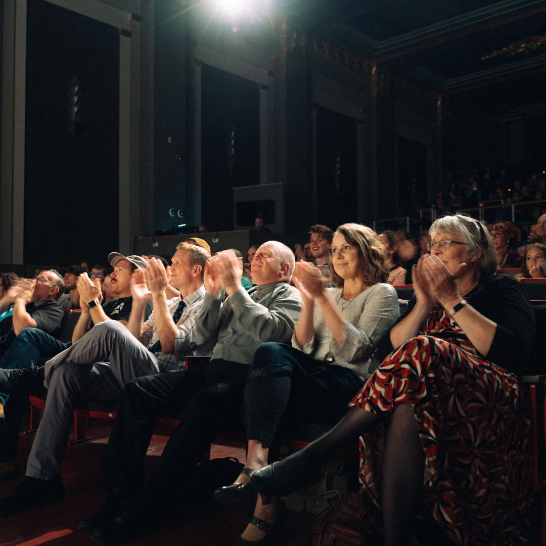 facing the audience applauding a performance at the Romance Theater