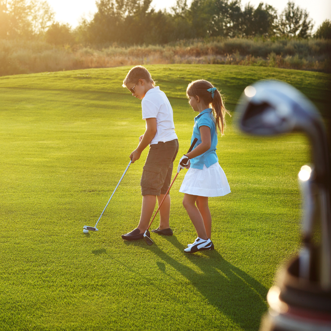 two young kids on a golf course with clubs