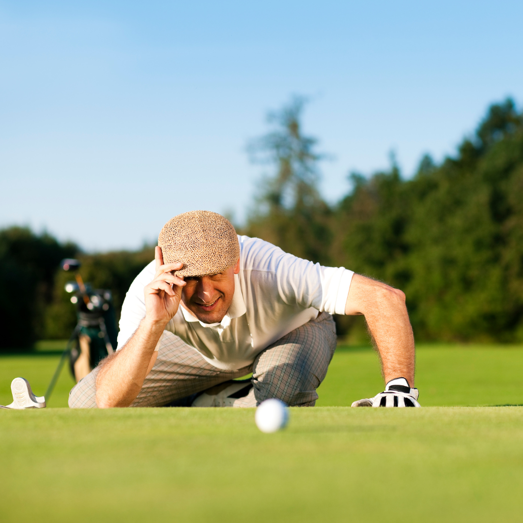 older man on a golf course checking the sight of his golf ball on the ground