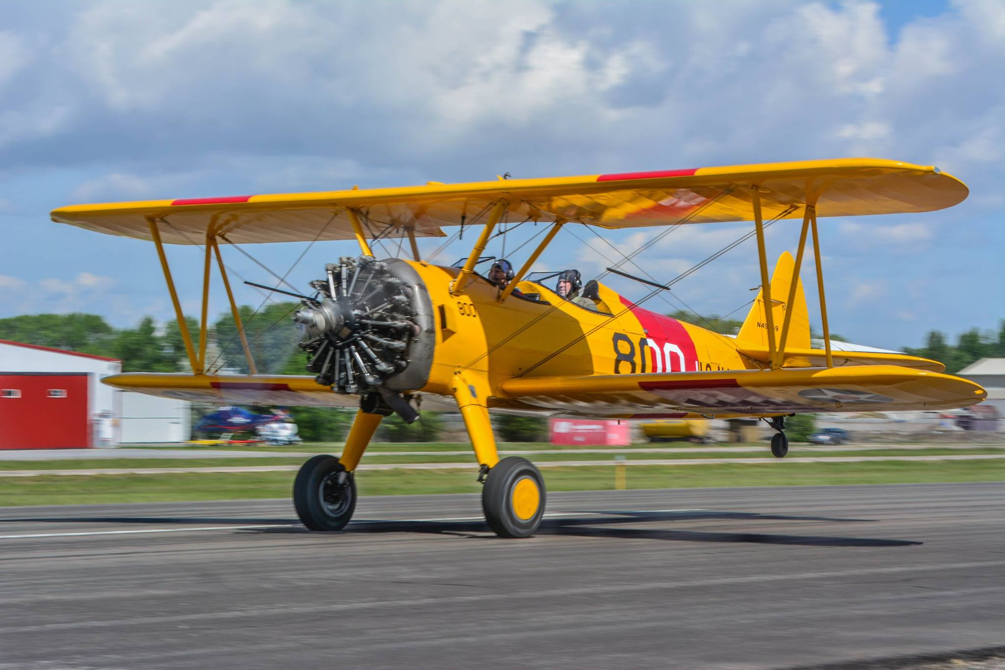 yellow boeing stearman plane landing on the runway