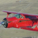 red airplane in the sky, photo shot from above with fields on the ground 