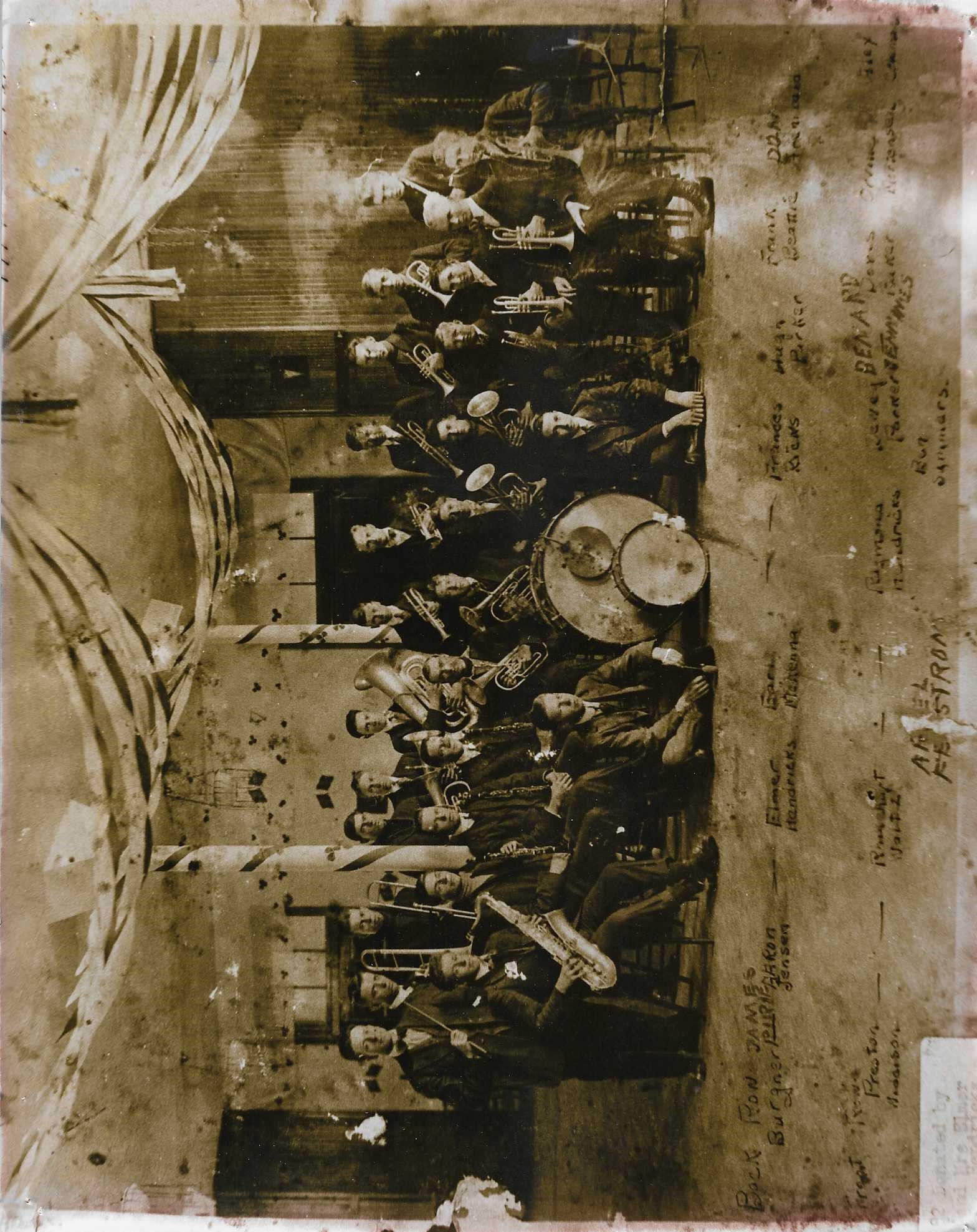 Old sepia photo of a large group of musicians with their instruments inside the Tabernacle.