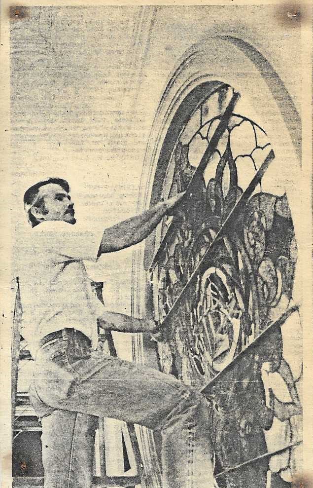 Old sepia photo of a man working on restoration of the circular stained glass window in the Tabernacle.