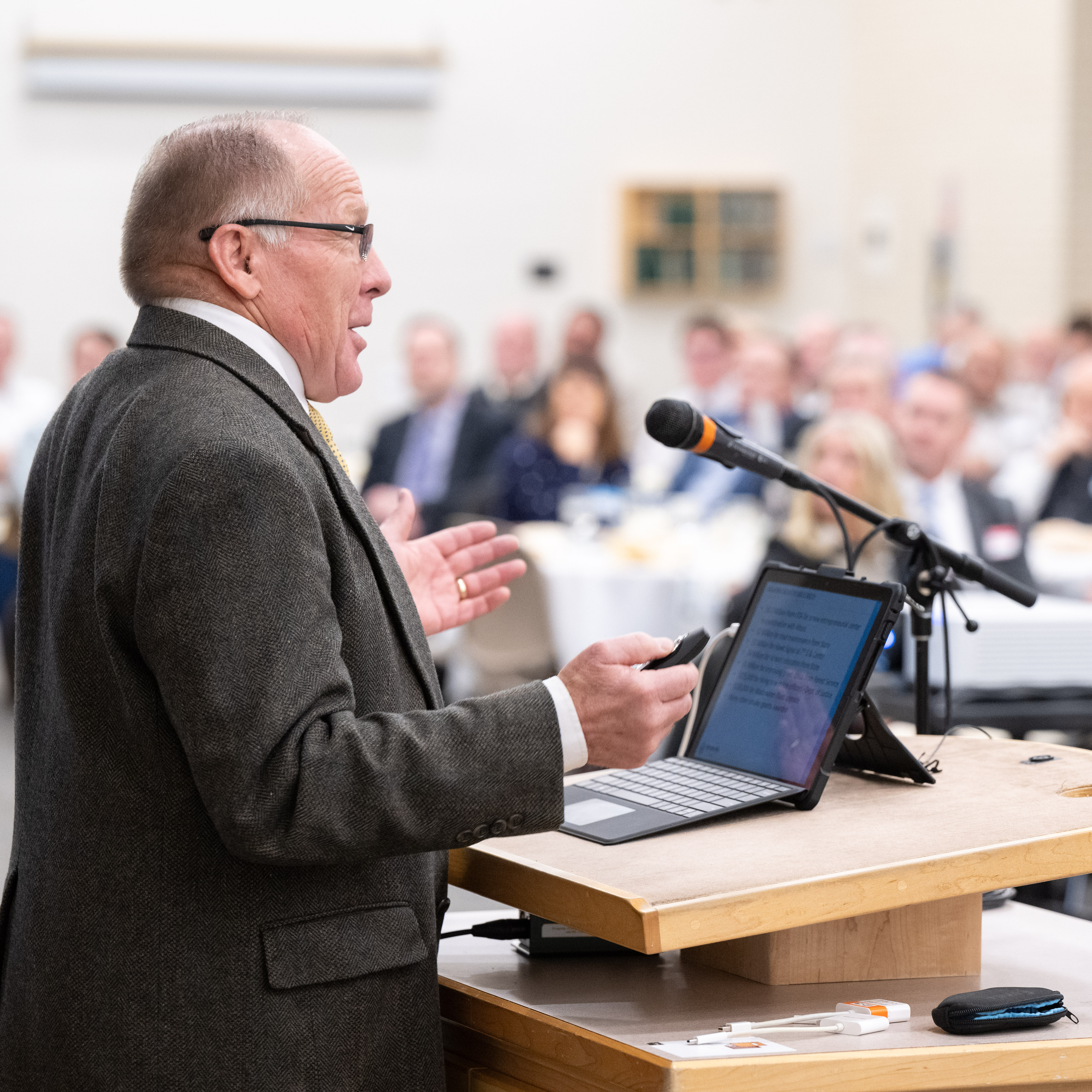 picture of Rexburg Mayor at a podium speaking to a blurry crowd in the background