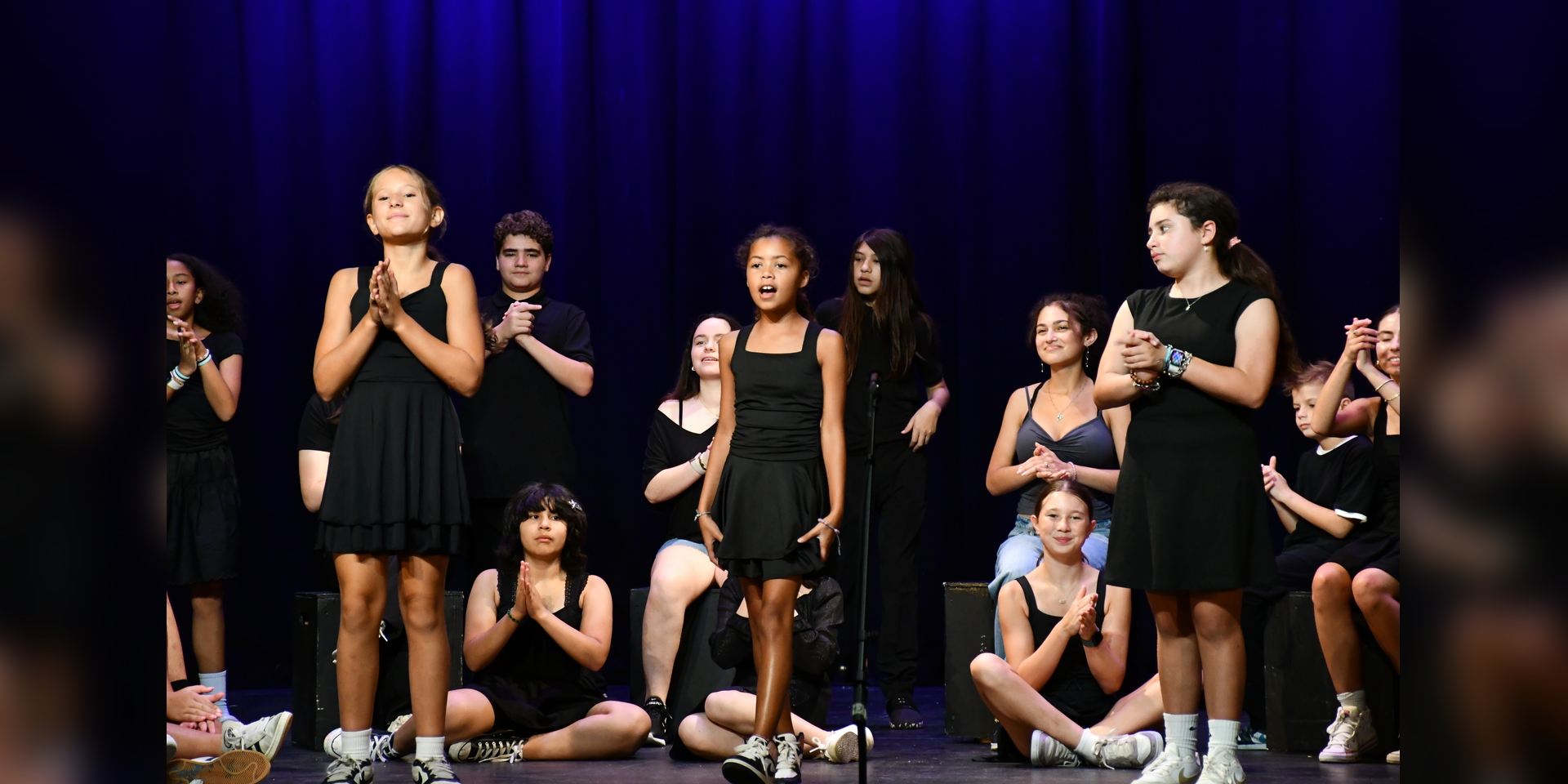 students in black outfits performing and dancing on stage