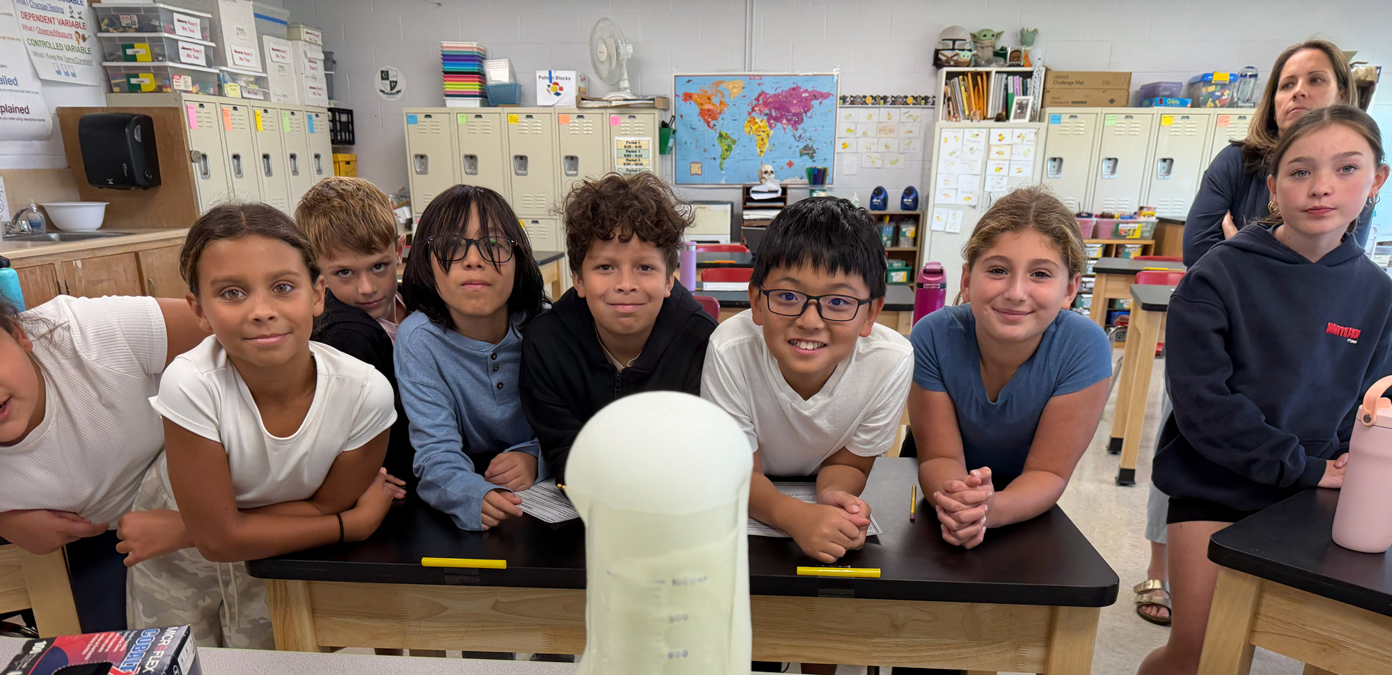 Students smiling at camera while working on project.