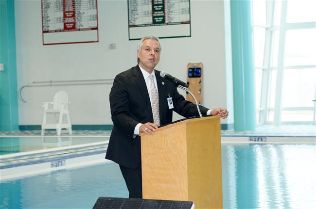 Male in the pool area speaking in a podium 