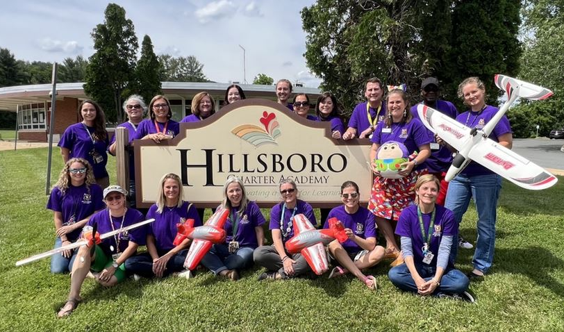 people in purple shirts in front of hillboro sign