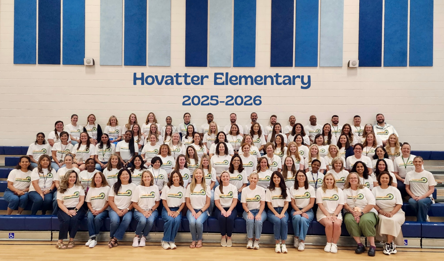 Picture of the 2025-2026 Hovatter Staff wearing their staff shirts seated on the gym bleachers