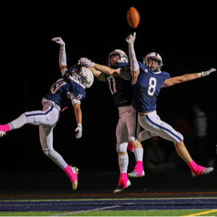 Members of the Champe football team jump and reach for a football in the air.