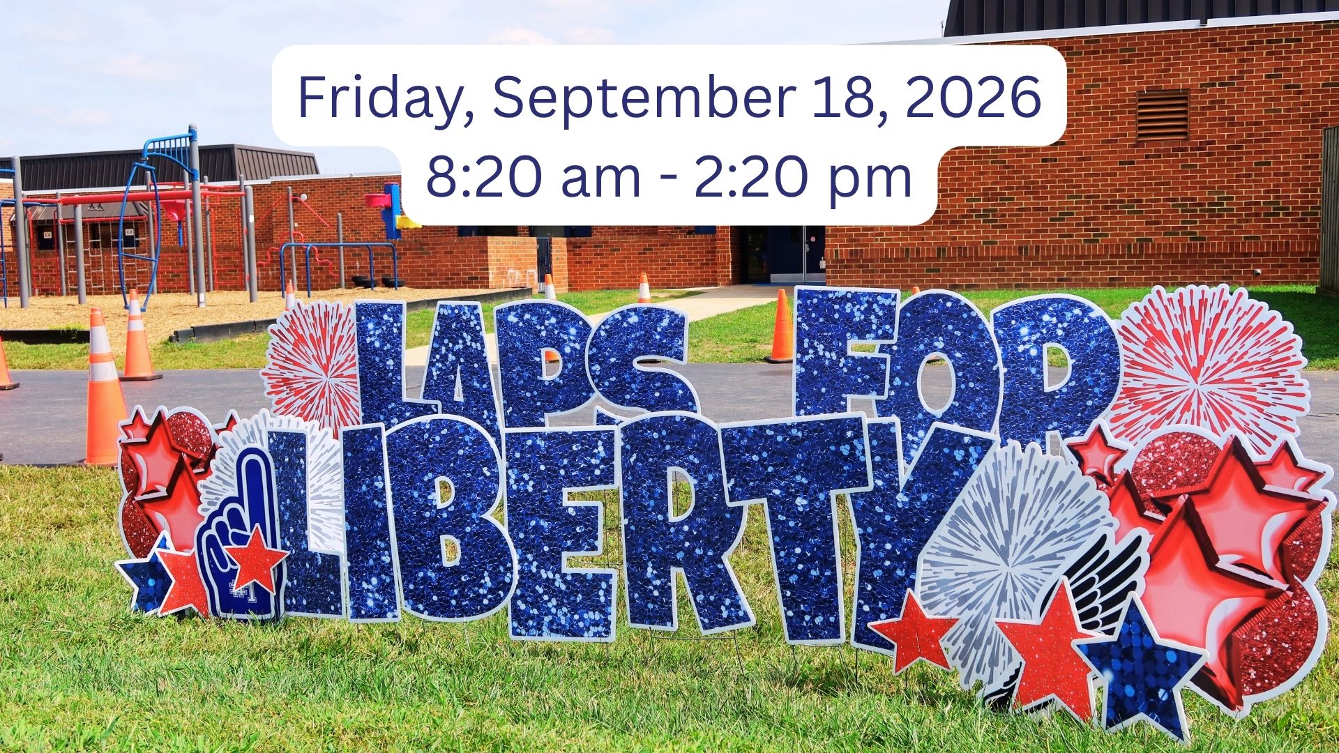 A colorful sign on a lawn with the words "LAPS FOR LIBERTY" and patriotic elements. Behind the sign is a brick building.