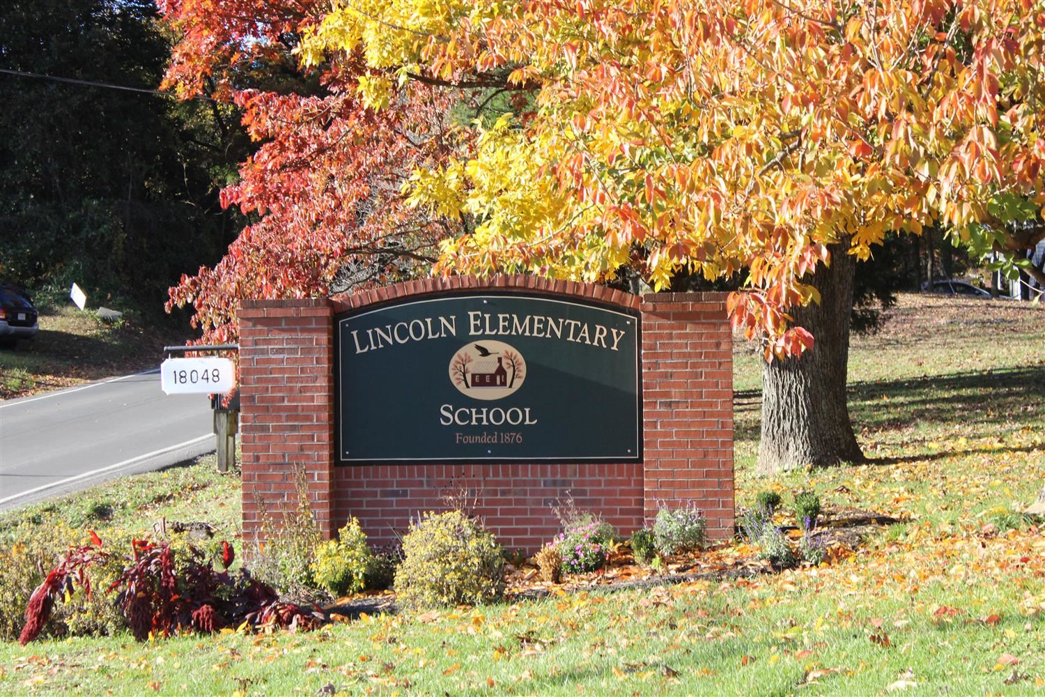 Front of Lincoln Elementary School sign with tree in fall, the leaves are yellow and orange 