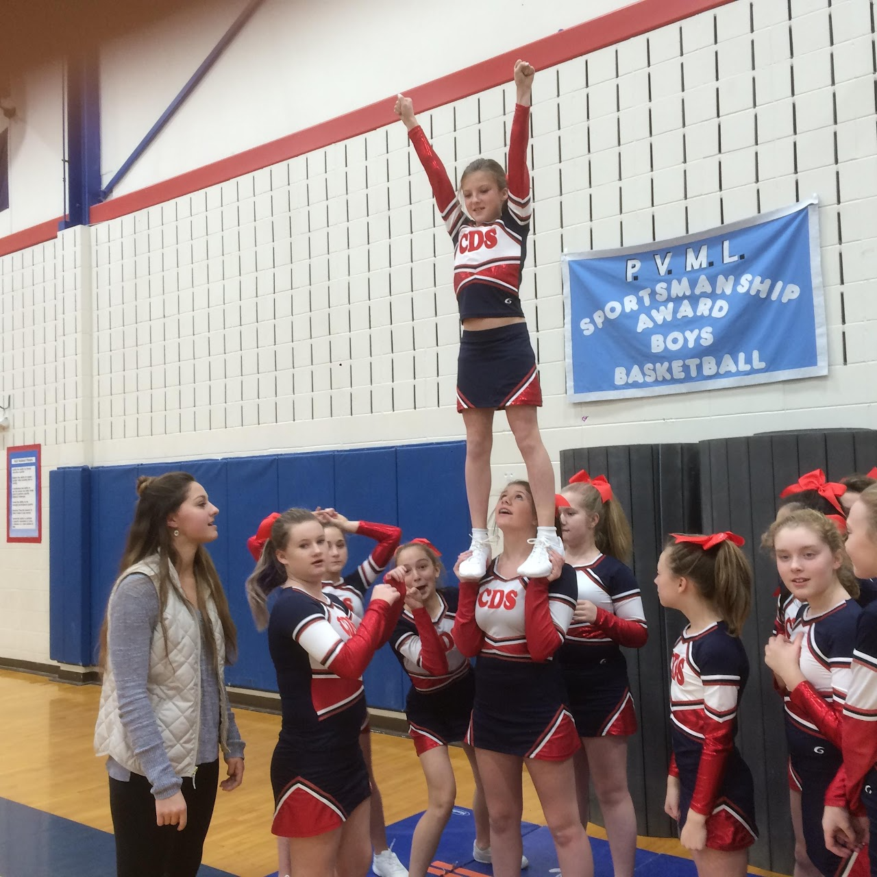Cheerleading team doing stunts with coach on the side