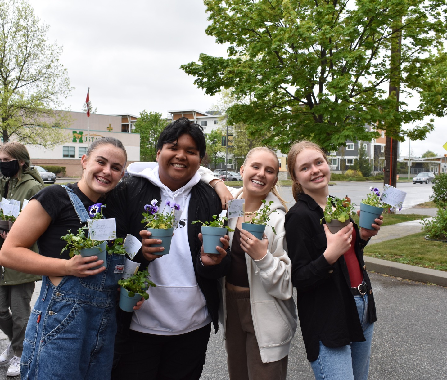 students gathered outside the school building with plants