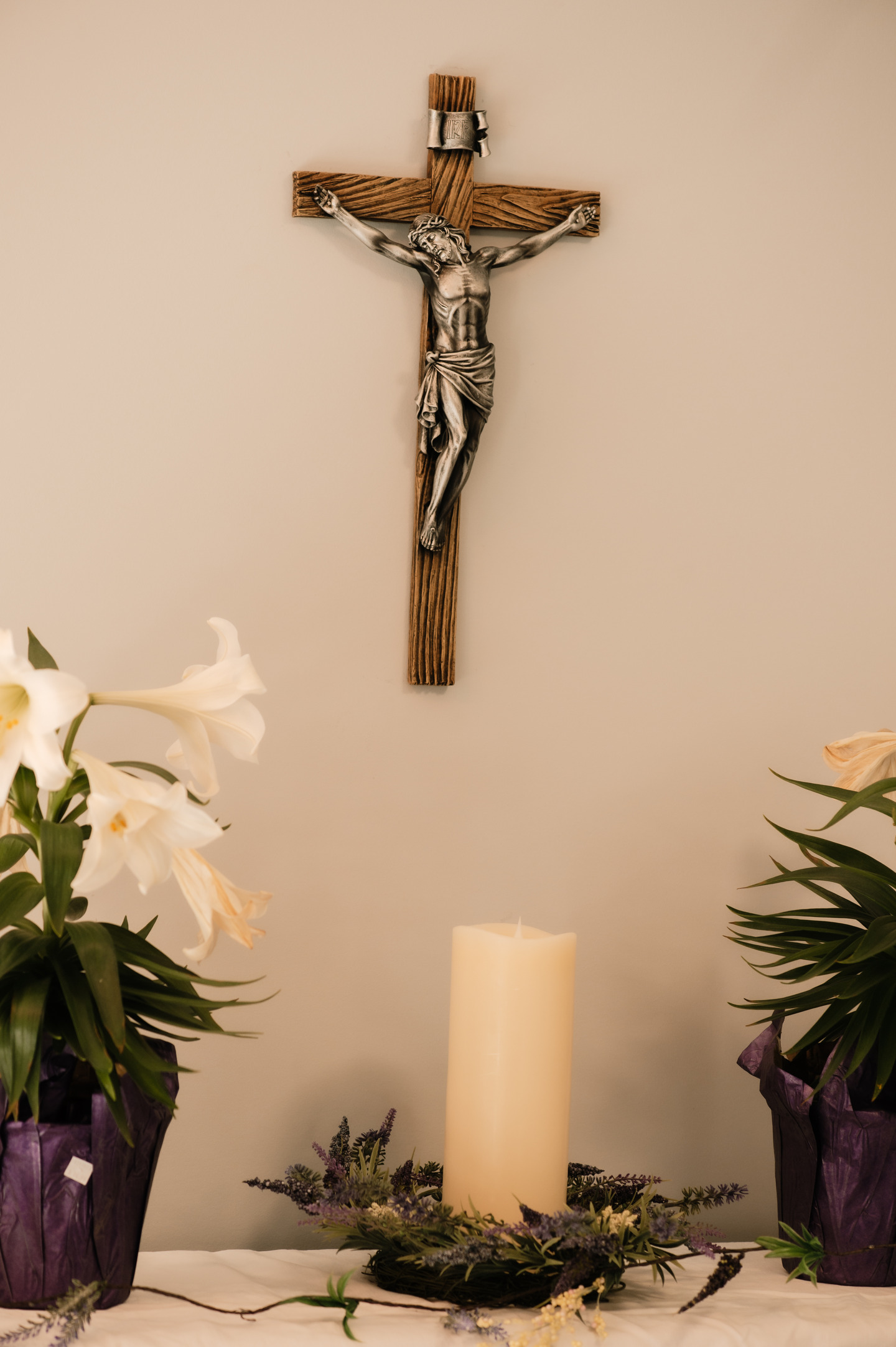 picture of a setting with a candle on a table and a cross on the wall