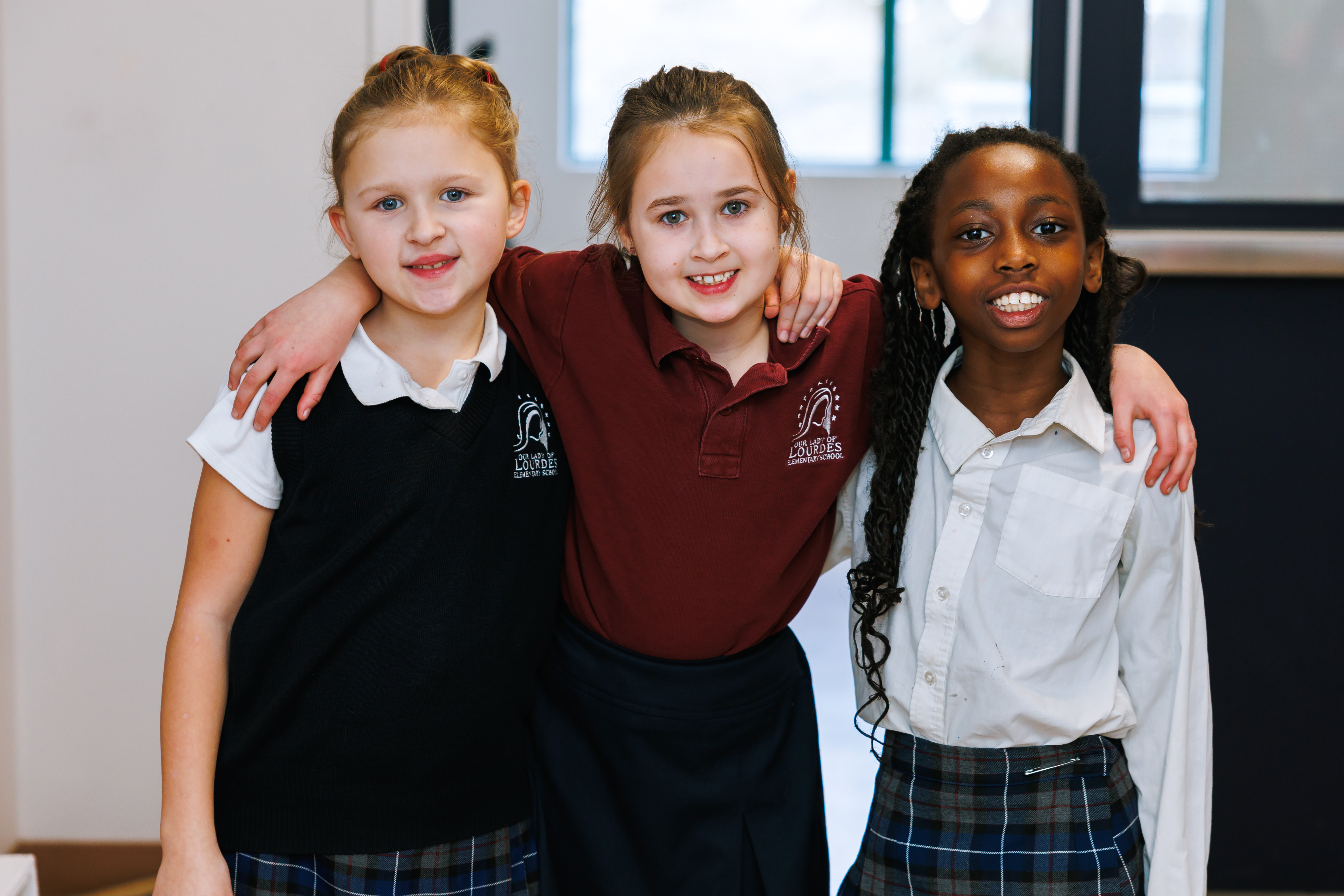 three girls in uniform with arms around each other