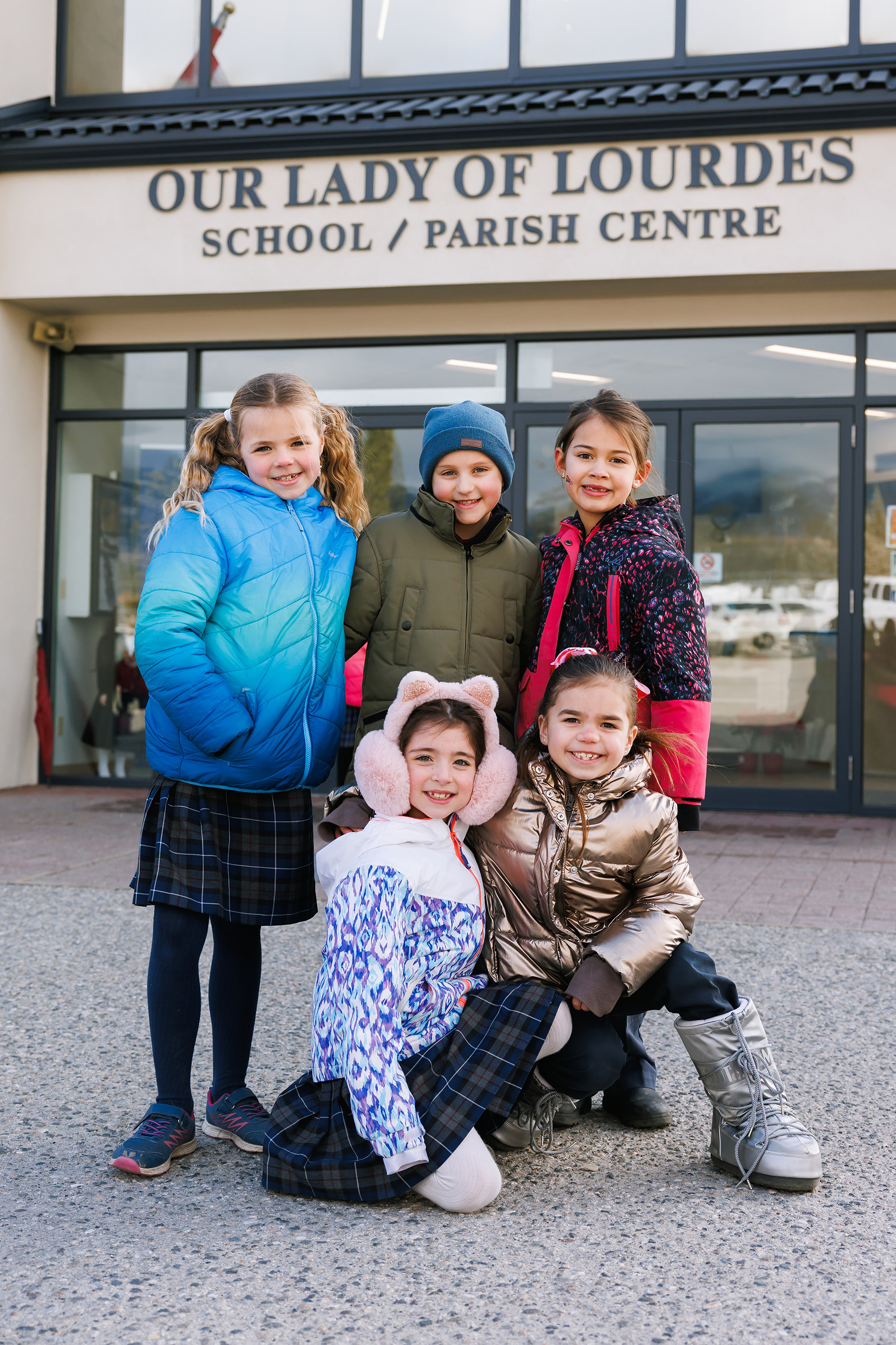 students in jackets in front of Our Lady of Lourdes School doors